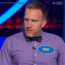 a man wearing a purple shirt and a bow tie has a name tag that says kris