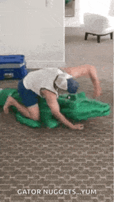 a man is kneeling on the floor playing with a crocodile costume .