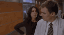 a man and a woman are standing next to each other in a hallway and the woman is looking at the man .