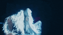 a woman in a white dress with angel wings is sitting on the floor