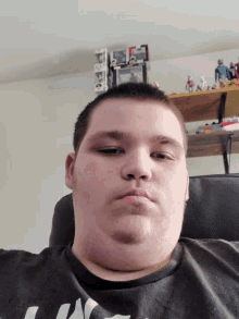 a man in a black shirt with the word army on it looks at the camera