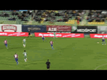 a group of soccer players are playing on a field with advertisements for air and super sport
