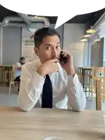 a man talking on a cell phone in front of a domino 's pizza sign