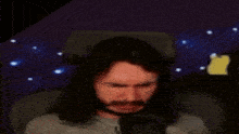 a man with long hair and a beard is making a funny face in front of a microphone