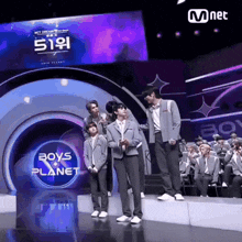 a group of boys standing on a stage in front of a boys planet sign