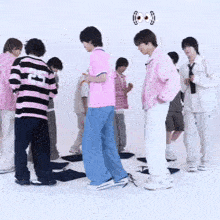 a group of young men are standing in a circle with one wearing a pink shirt with the number 21 on it .