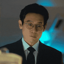 a man wearing glasses and a suit and tie looks at something