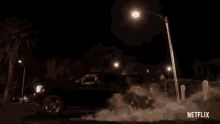 a car is driving down a street at night and smoke is coming out of the tires ..