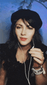 a woman wearing a black beret and earbuds looks at the camera