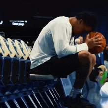 a man sits on a bench with a basketball in his hand