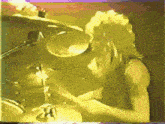 a man playing a drum set with a purple and yellow background