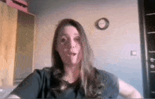 a woman is talking on a video call in a room with a clock on the wall behind her .