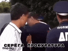 a man in a white shirt is being escorted by a man in a blue hat with the letter a on it