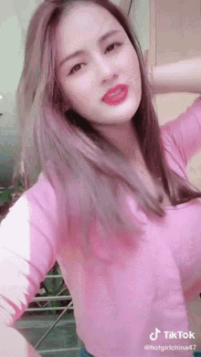 a woman in a pink shirt is making a funny face while dancing .