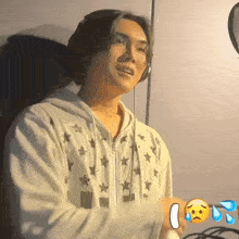 a man wearing headphones and a white hoodie with stars