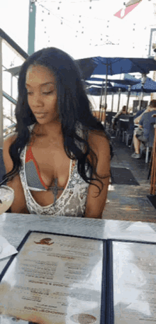 a woman in a bikini sits at a table with a menu on it