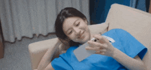 a woman in a scrub is laying on a couch looking at her phone .