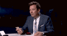 a man in a suit and tie is smiling while holding a phone