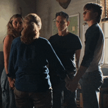 a group of people are holding hands in a room