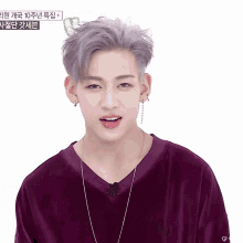 a young man wearing a purple shirt and earring looks at the camera