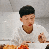 a young man is eating a bowl of food with a fork and knife