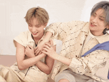 two young men are playing with each other and one is wearing a blue sweater