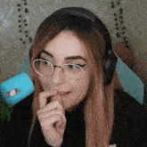 a woman wearing glasses and headphones has a sticker on her finger that says coca cola