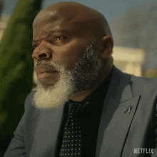 a man with a beard is wearing a suit and tie with netflix written on the bottom right