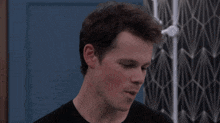a man in a black shirt is smiling in front of a shower head