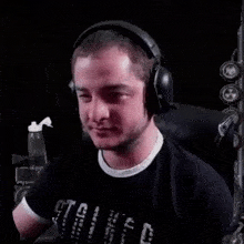 a man wearing headphones and a black shirt is sitting in a chair in a dark room .