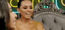 two women are sitting on a couch talking to each other and smiling .