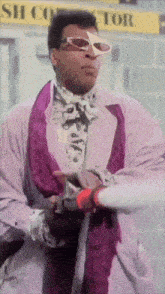 a man wearing sunglasses and a purple coat is standing in front of a silicon connector sign