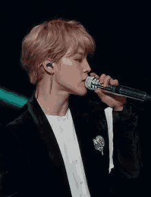 a man in a suit is singing into a microphone while wearing earphones .