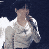 a woman singing into a microphone with wings on her arms