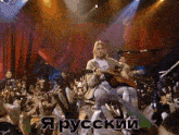 a man playing a guitar in front of a crowd with the word russian in the corner