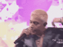 a man is singing into a microphone with a purple background
