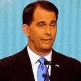 a man wearing a suit and tie is speaking into a microphone