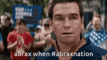 a man is standing in front of a crowd with the words abrax when # abraxnation written on his face .