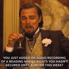 a man in a tuxedo holds a glass of wine and says " you just added an audio recording "