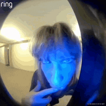 a person 's face is visible through a doorbell with ring written on the bottom