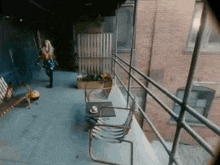 a woman is walking down a balcony next to a brick building .