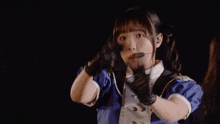 a girl wearing a microphone and gloves holds her hands in the air