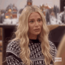 a woman with blonde hair is wearing a black and white sweater with christian dior on it