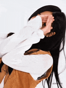 a woman with long black hair covering her face with her hands ..