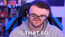 a man wearing glasses and a hoodie is making a funny face while sitting in a gaming chair .