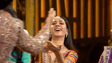 a woman in a colorful dress is laughing while another woman holds her hand to her face .