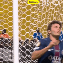 a man in a qatar jersey is standing in front of a soccer goal net