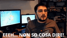 a man with glasses and a beard is sitting in front of two computer monitors and says eeeh ... non so cosa dire
