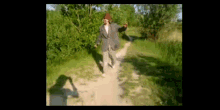 a man in a hat is walking down a dirt road