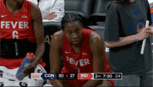 a fever basketball player sits on the bench watching the game